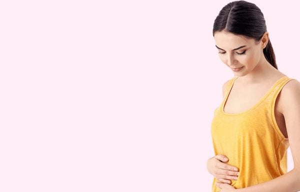 Mulher grávida olha para a barriga se formando: o primeiro trimestre de gestação traz muitas mudanças