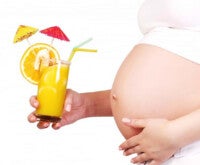 Mulher grávida segura um copo de suco de laranja: alimentação saudável é importante também no segundo trimestre de gravidez