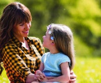 Mãe olha para filha em seu colo em um parque: a constipação atinge crianças e adultos