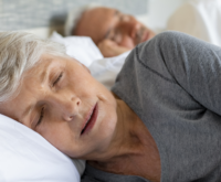 Mulher madura dormindo em cama: a relação entre dificuldades com sono e saúde cardíaca
