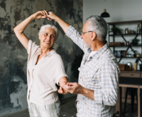 Casal maduro dançando na sala: o tratamento sem interrupções ajuda a manter a qualidade de vida