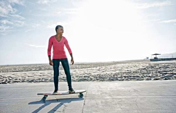 Mulher de meia idade anda de skate na praia em alusão a adotar um estilo de vida saudável no trabalho