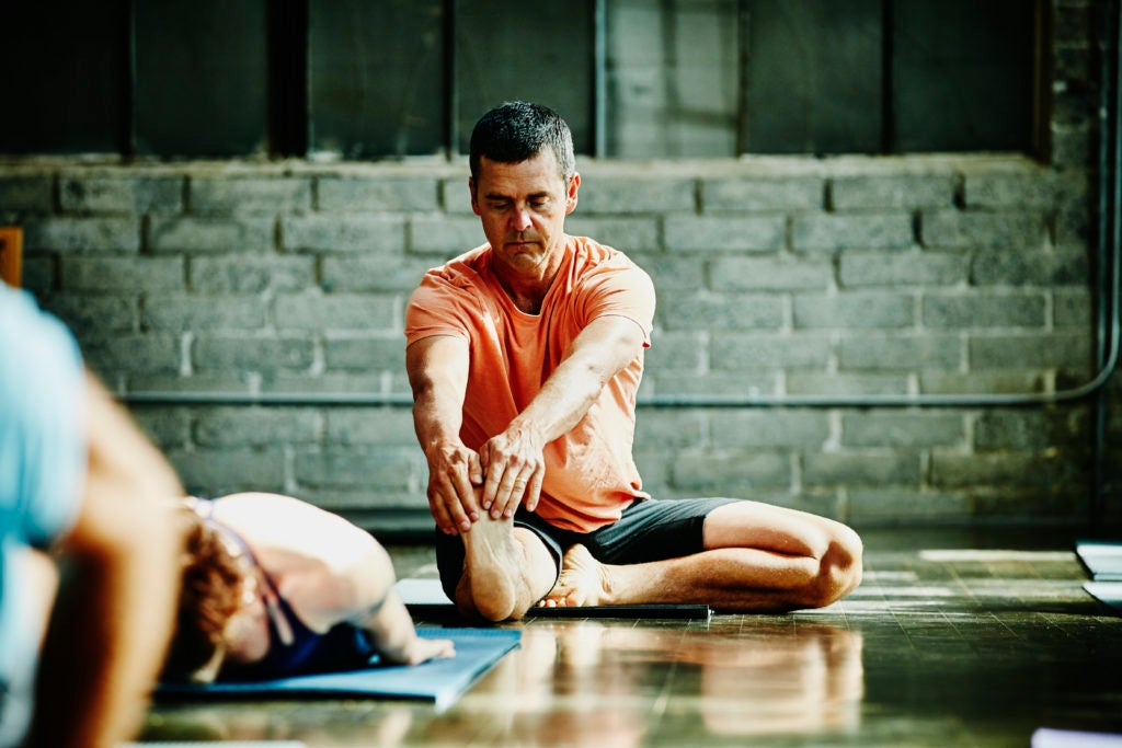 Homem praticando ioga em estúdio: impacto positivo do exercício na redução do colesterol
