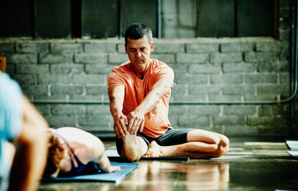 Homem praticando ioga em estúdio: impacto positivo do exercício na redução do colesterol