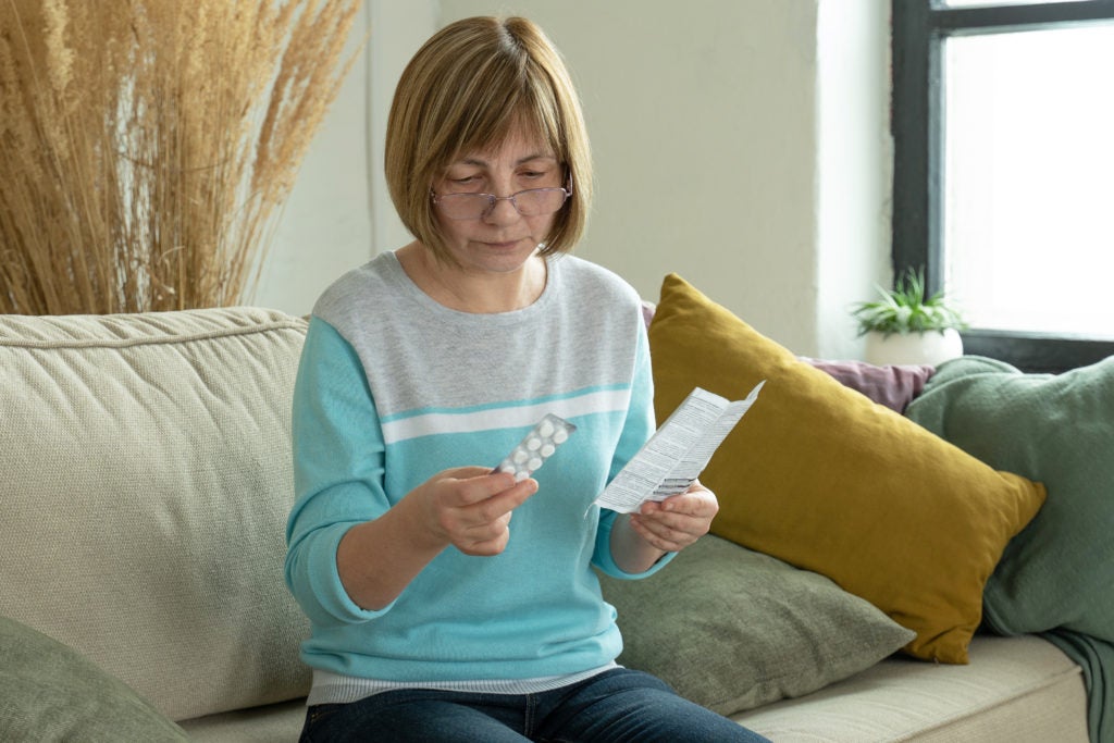Mulher de meia-idade tomando seu medicamento ilustra a importância da adesão ao tratamento na menopausa