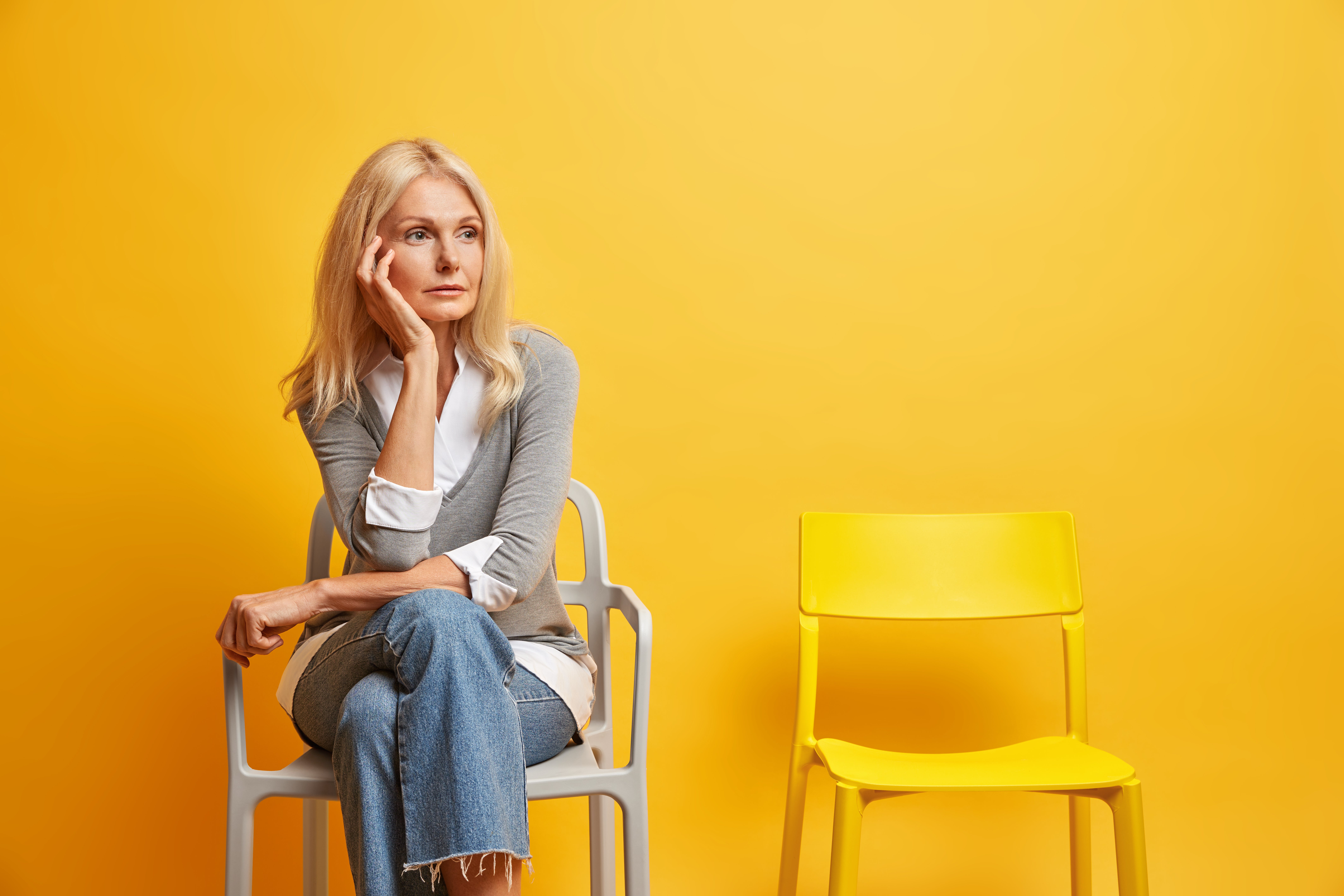 Mulher na menopausa sentada em cadeira sozinha