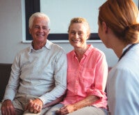 Profissional de saúde conversa com casal de meia idade, mostrando que existe tratamento para os sintomas da menopausa
