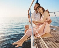 Casal abraçado em deck de barco em alto mar: a importância de aderir ao tratamento da vertigem para se sentir melhor