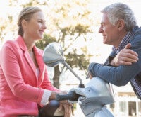 Casal de meia idade conversando em uma scooter sobre quais são os sintomas da menopausa