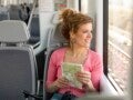 Mulher com mapa nas mãos sentada viajando de trem olha pela janela