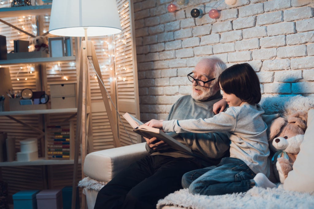 Avô e neto lendo um livro na sala 